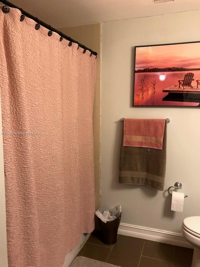 full bathroom with toilet, a shower with curtain, baseboards, and tile patterned floors