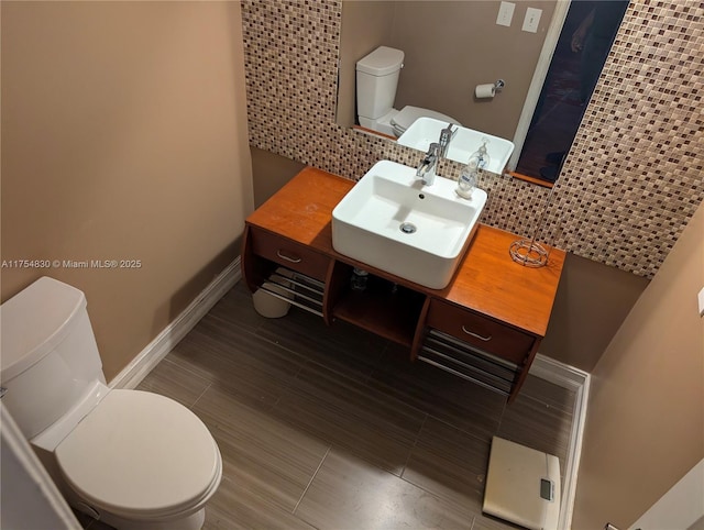 bathroom featuring toilet, baseboards, and a sink