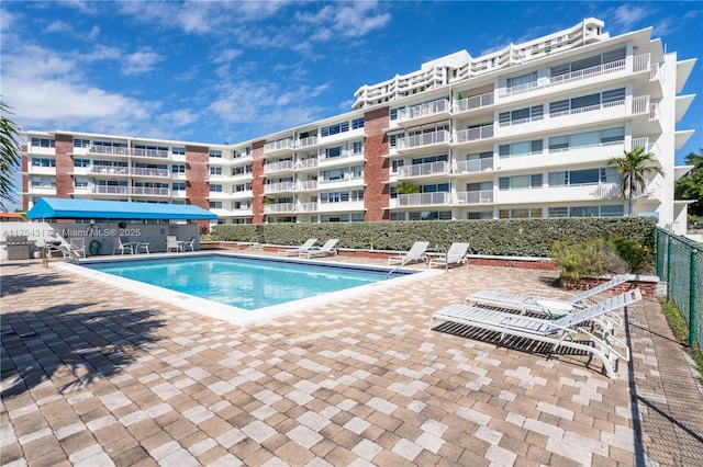 community pool with a patio area and fence