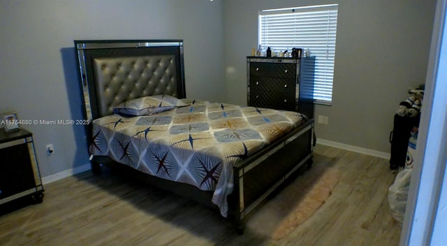 bedroom with multiple windows, baseboards, and wood finished floors