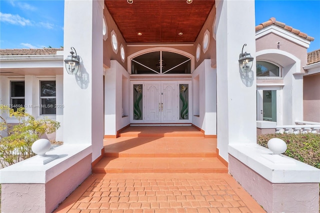 doorway to property with a tile roof and stucco siding