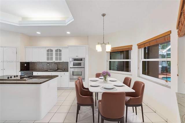 kitchen featuring decorative backsplash, dark countertops, glass insert cabinets, stainless steel double oven, and a sink