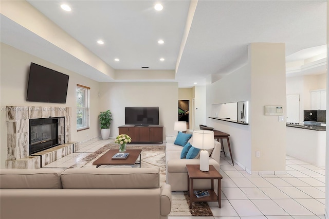 living area with a tray ceiling, a fireplace, light tile patterned floors, recessed lighting, and baseboards