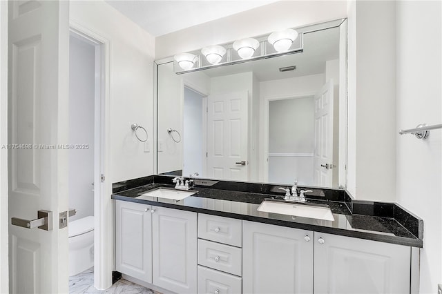 full bathroom featuring marble finish floor, a sink, toilet, and double vanity