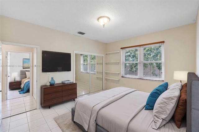 bedroom featuring light tile patterned floors, visible vents, and a textured ceiling