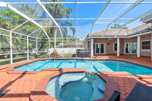 view of swimming pool featuring glass enclosure, fence, a pool with connected hot tub, french doors, and a patio area