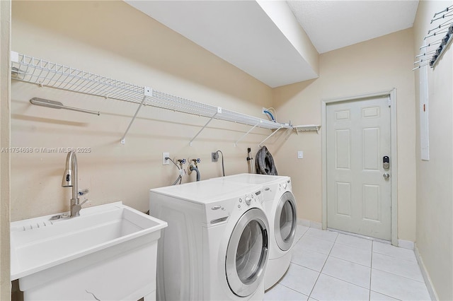 laundry area with laundry area, baseboards, washing machine and clothes dryer, a sink, and light tile patterned flooring