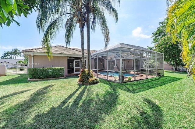 rear view of property featuring a tile roof, a yard, stucco siding, a lanai, and a fenced backyard