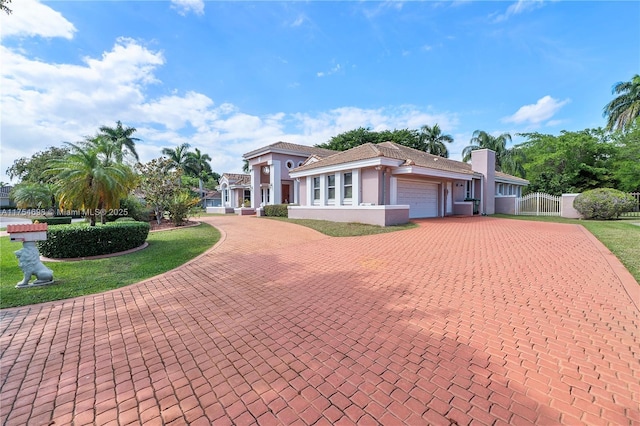 view of front facade featuring an attached garage, fence, decorative driveway, stucco siding, and a chimney