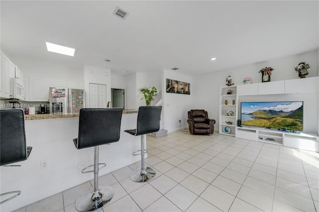 living area featuring visible vents and light tile patterned flooring