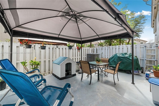 view of patio / terrace with outdoor dining space, central AC, fence, and a gazebo