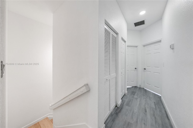 hallway with baseboards, visible vents, and wood finished floors