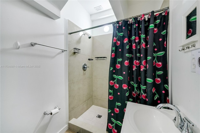 bathroom with visible vents, a sink, and tiled shower