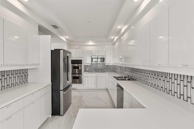 kitchen with stainless steel appliances, a sink, white cabinetry, decorative backsplash, and modern cabinets