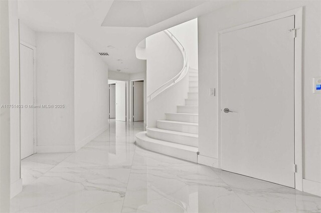 foyer with stairs, marble finish floor, and visible vents