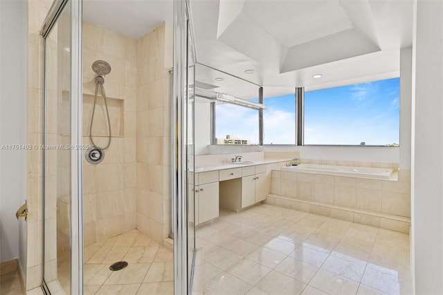 bathroom featuring a tray ceiling, a garden tub, a shower stall, and vanity