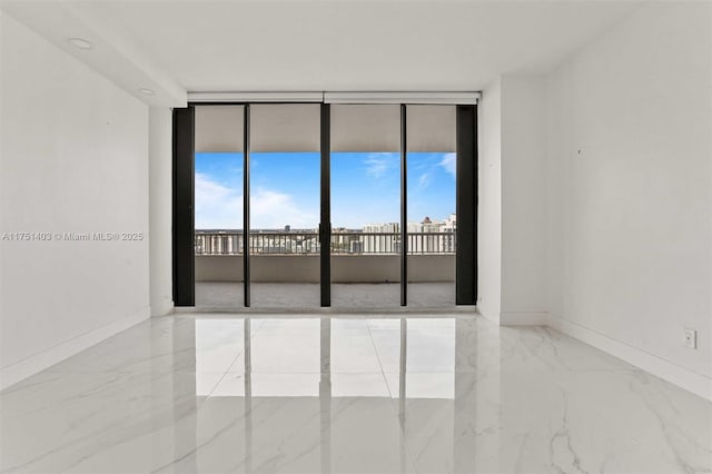 unfurnished room with a wall of windows, marble finish floor, and baseboards