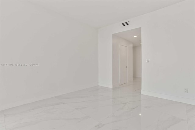 spare room with marble finish floor, visible vents, and baseboards