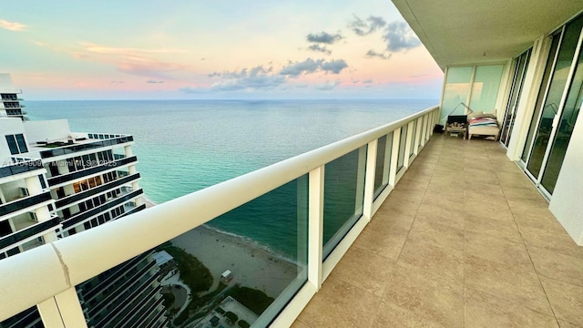 balcony at dusk featuring a water view