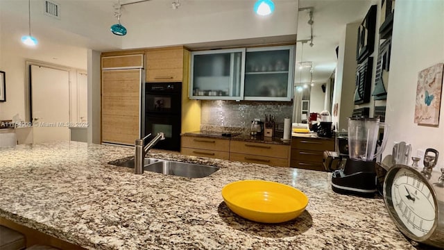 kitchen with visible vents, glass insert cabinets, dobule oven black, a sink, and backsplash