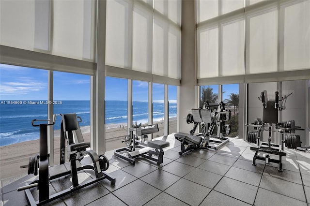 exercise room featuring a water view and a view of the beach