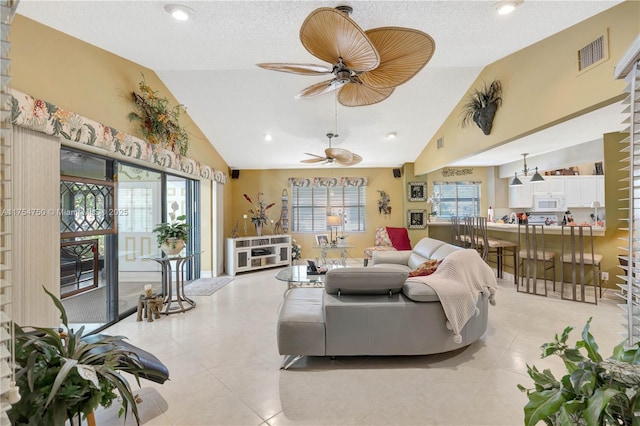 living room featuring vaulted ceiling, ceiling fan, visible vents, and a healthy amount of sunlight
