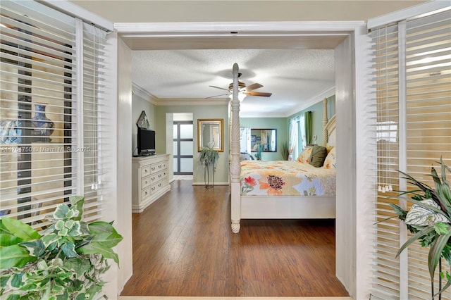 bedroom with a textured ceiling, wood finished floors, a ceiling fan, baseboards, and ornamental molding