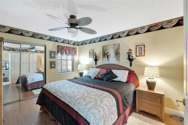 bedroom with a closet, hardwood / wood-style floors, a ceiling fan, a textured ceiling, and baseboards