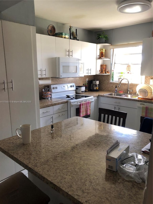 kitchen with white appliances, tasteful backsplash, white cabinets, and a sink