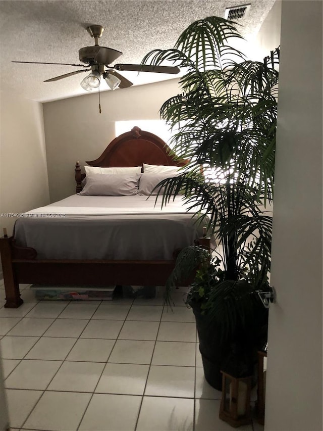 bedroom with a ceiling fan, visible vents, light tile patterned flooring, and a textured ceiling