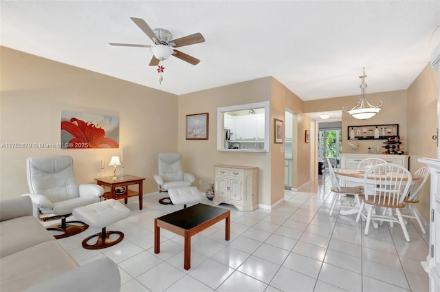 living area with light tile patterned floors, ceiling fan, and baseboards