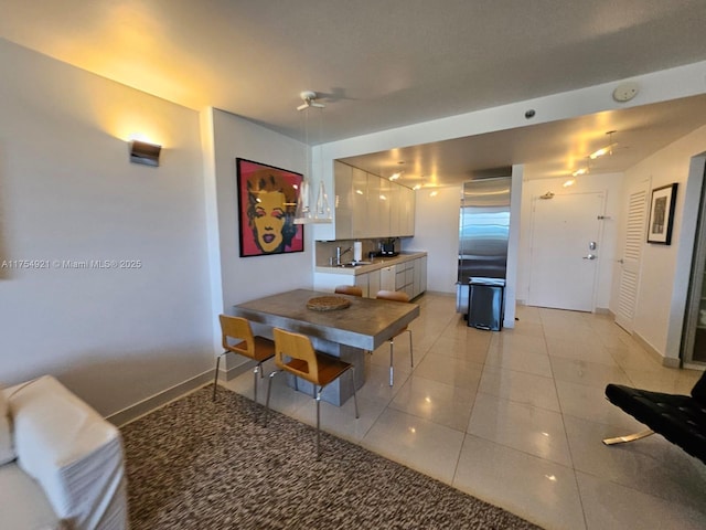 kitchen with light tile patterned floors, baseboards, high quality fridge, white cabinetry, and a sink