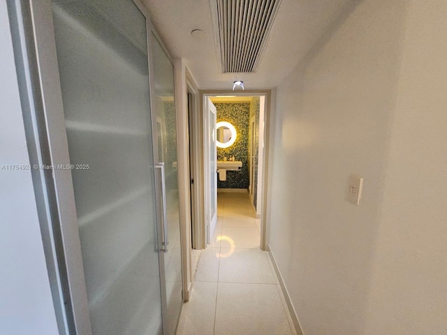 hall featuring light tile patterned flooring, visible vents, and baseboards