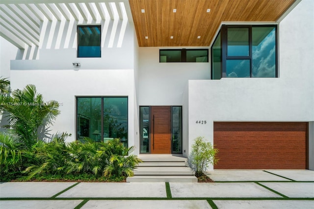 view of exterior entry with a garage and stucco siding