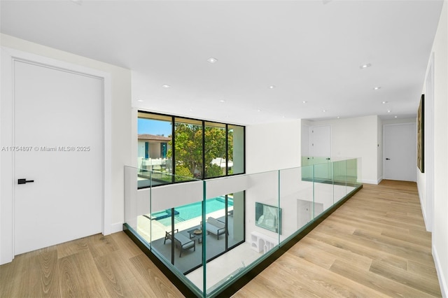 hallway with a wall of windows, recessed lighting, and light wood-style floors