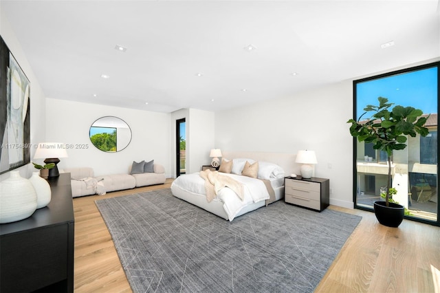 bedroom with light wood-style floors, floor to ceiling windows, and multiple windows