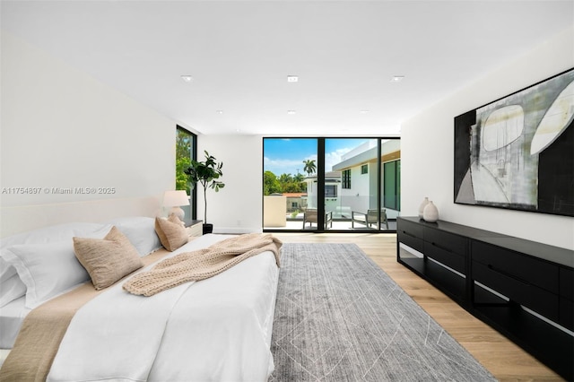 bedroom featuring light wood-style flooring, floor to ceiling windows, and access to outside