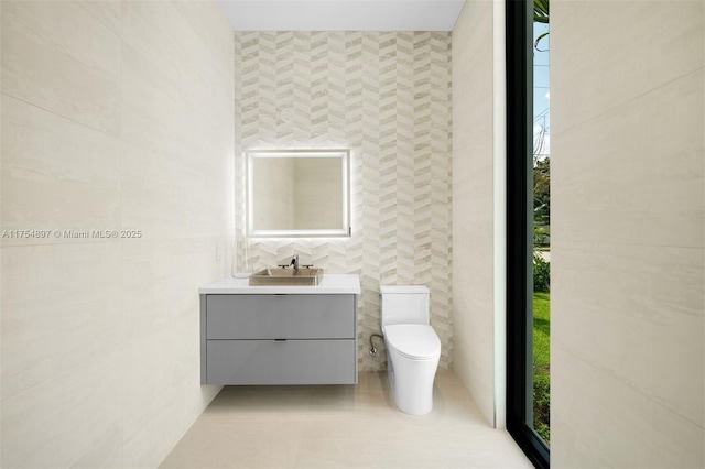 bathroom featuring toilet, tile patterned flooring, tile walls, and vanity