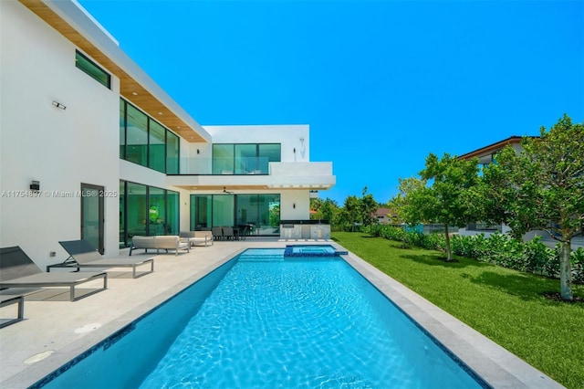 view of swimming pool with a pool with connected hot tub, a lawn, and a patio