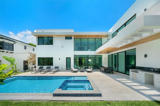 back of property featuring a patio, a pool with connected hot tub, and stucco siding