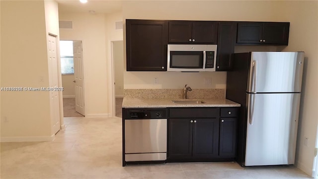 kitchen with a sink, visible vents, light stone counters, and appliances with stainless steel finishes