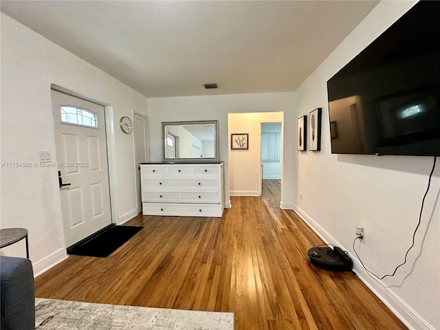 foyer featuring baseboards, visible vents, and wood finished floors