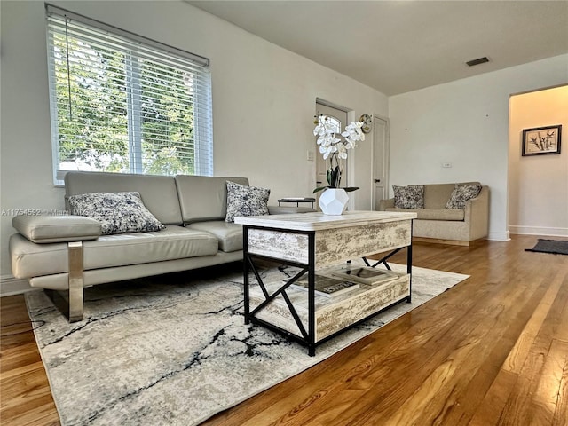 living area featuring visible vents, baseboards, and wood finished floors