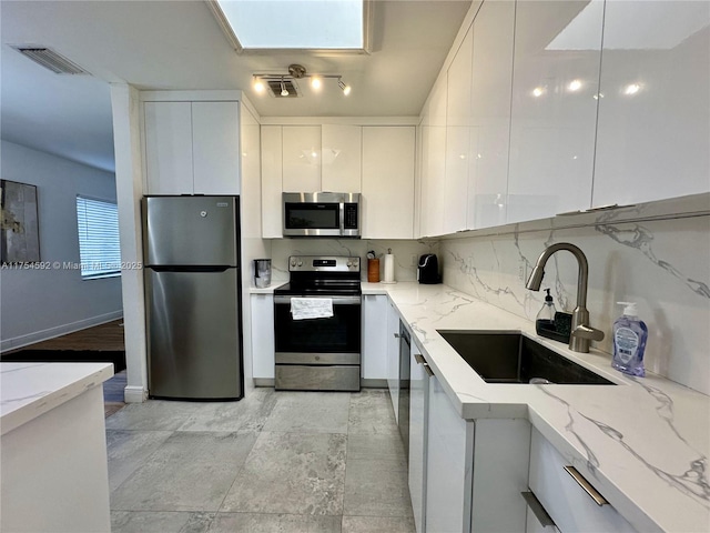 kitchen featuring visible vents, appliances with stainless steel finishes, white cabinetry, a sink, and modern cabinets