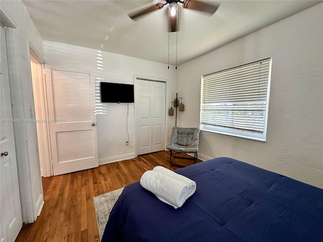 bedroom featuring a closet, ceiling fan, baseboards, and wood finished floors