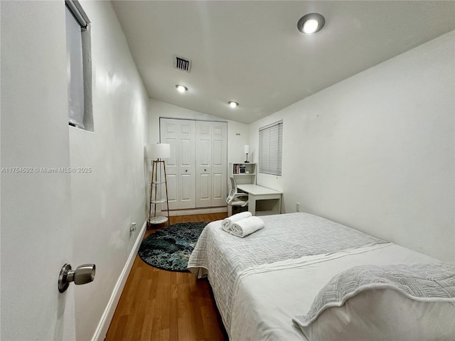 bedroom featuring lofted ceiling, a closet, visible vents, wood finished floors, and baseboards