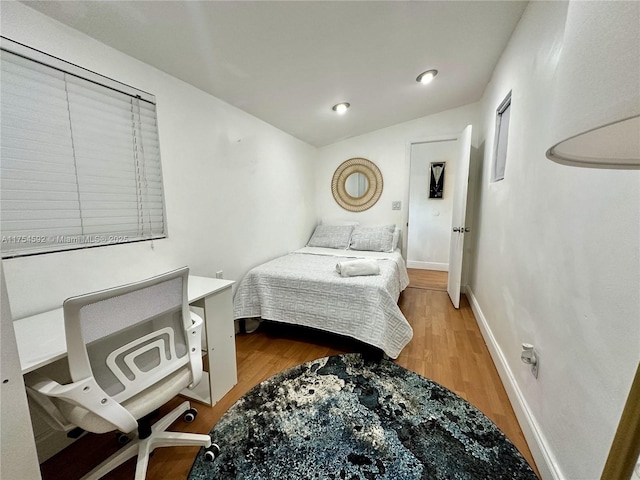 bedroom featuring lofted ceiling, wood finished floors, and baseboards