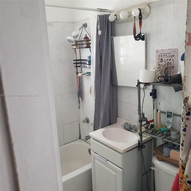 bathroom with toilet, vanity, tile walls, backsplash, and shower / bath combo