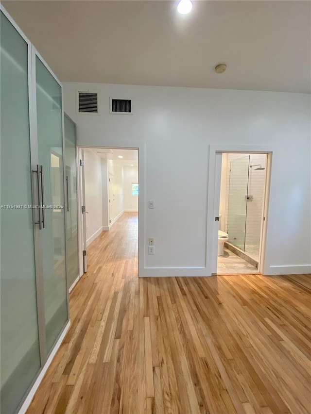 empty room with visible vents, light wood-style flooring, and baseboards