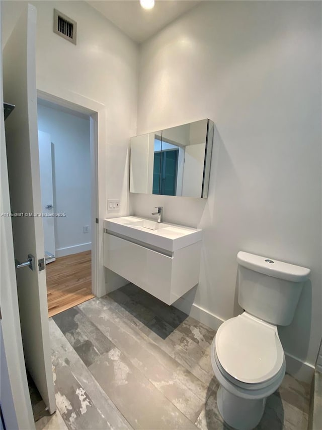 bathroom with toilet, baseboards, visible vents, and vanity